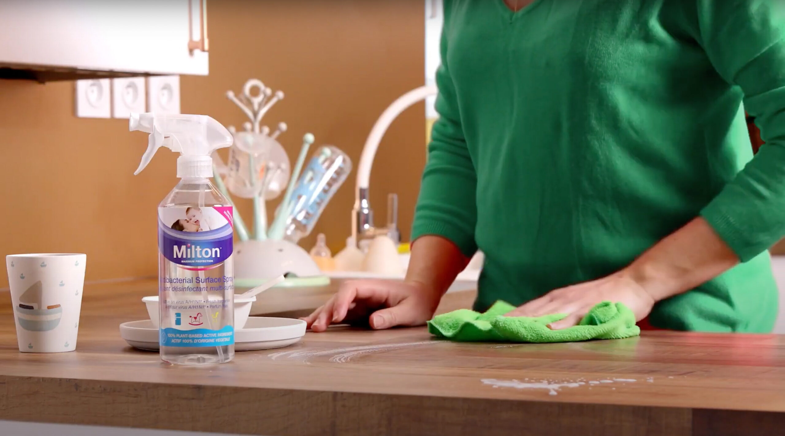 Woman cleaning kitchen counter using Milton antibacterial surface spray